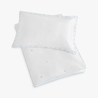 White pillowcase and toddler duvet with embroidered blue star pattern on a white background