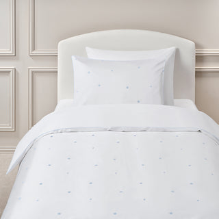White bedding set with subtle embroidered star pattern on a bed in a bedroom setting.