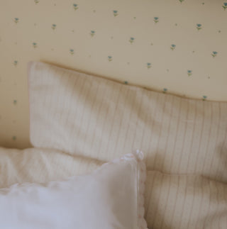 Textured pillows on a bed with a patterned wall in the background