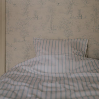 Striped bedspread and pillow on a bed with floral wallpaper.
