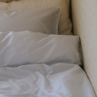 Close-up of blue bedding on a bed with a neutral headboard.