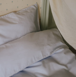 Close-up of blue bedding on a bed with a curtain in the background