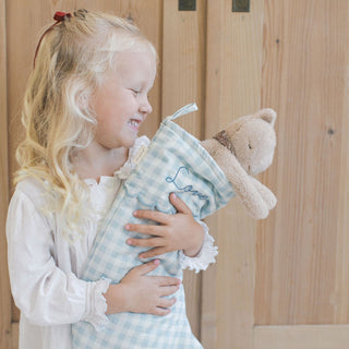 Little girl hugging our Gingham Holiday Stocking with a sweet stuffed animal inside.