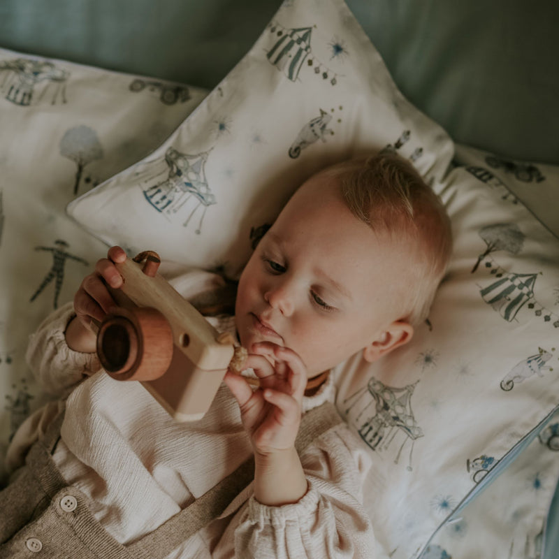 Baby playing with a toy camera while laying on a patterned pillow