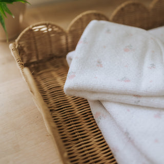 Folded white towel with pink patterns on a wicker basket