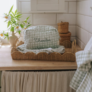 Picnic Gingham pouch with 'Theodor' branding on a wooden surface with wicker baskets and flowers.