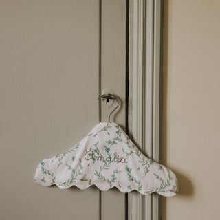 Floral-patterned hanger with 'Amalia' text on a beige wall.