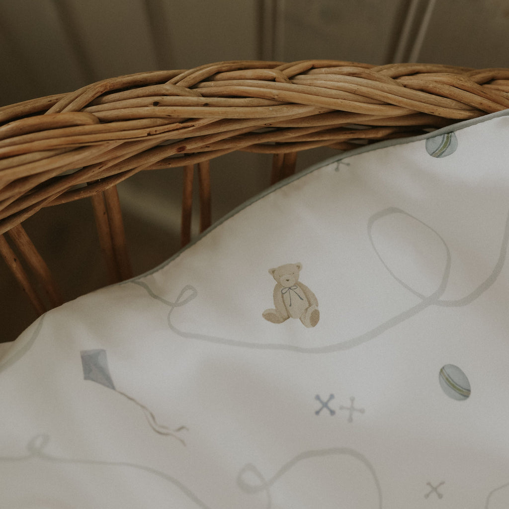 Close-up of a wicker basket with a decorative pillow featuring teddy bear illustrations.