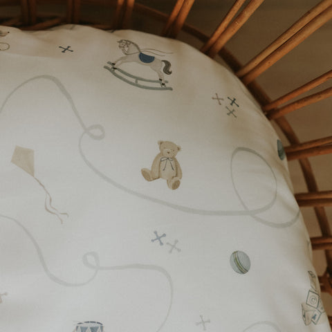 Baby crib with white sheet featuring simple illustrations of a bear, rocking horse, and toys.