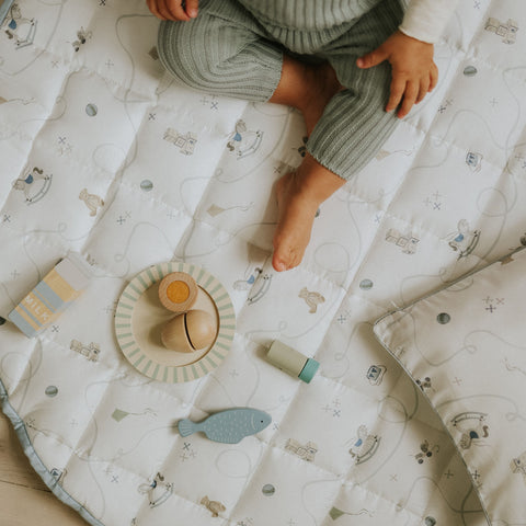 Child playing on a patterned mat with toys nearby