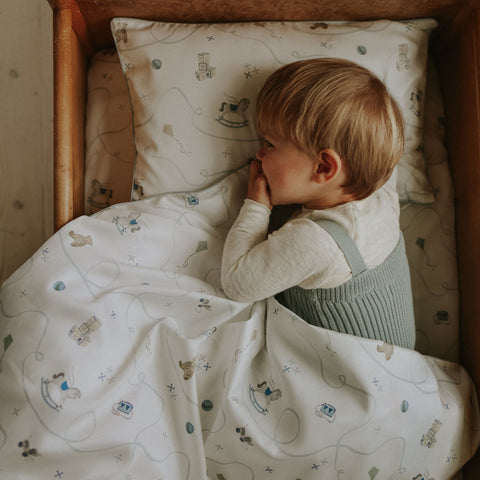 Child lying in bed with patterned bedding and pillow