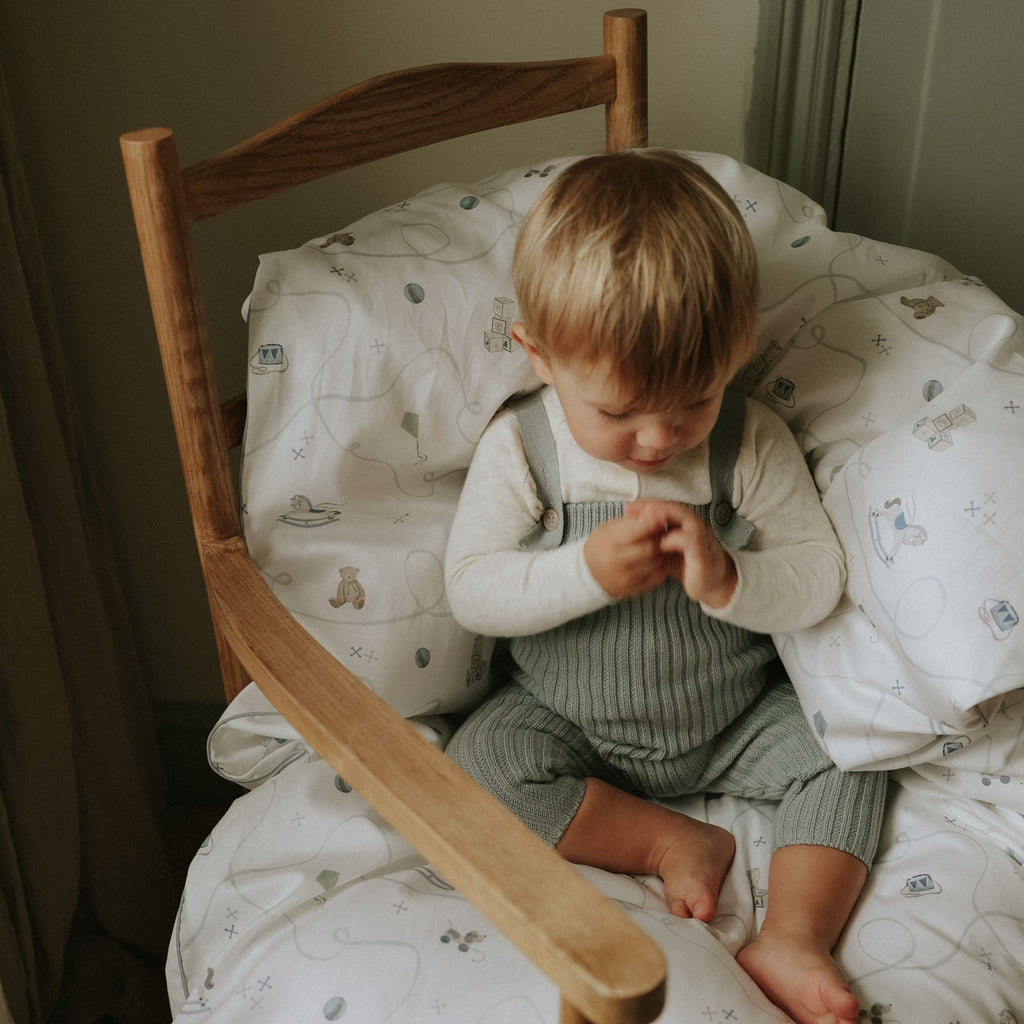Child sitting on a wooden chair with patterned cushion