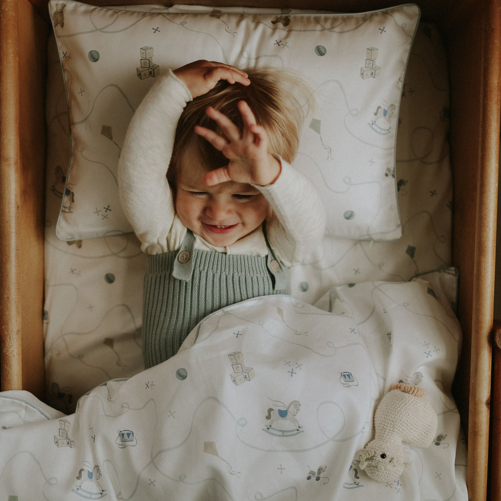 Child in a crib with patterned bedding and pillows