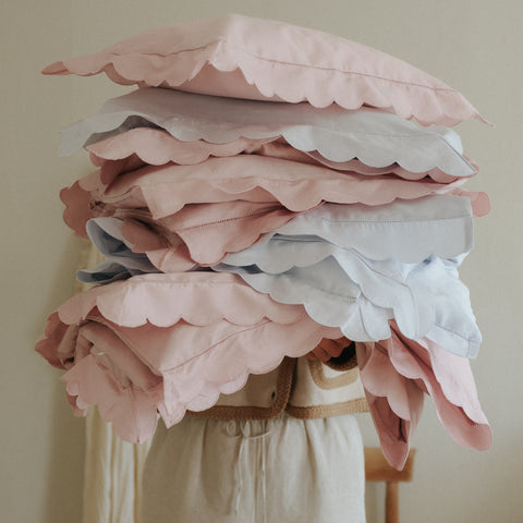 Scalloped Starlight bedding stacked in womans arms