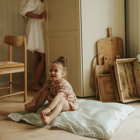 Green Gingham Toddler Duvet laying on the floor with child sitting on top