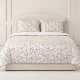 Woodland patterned bedding set on a bed with a neutral headboard.