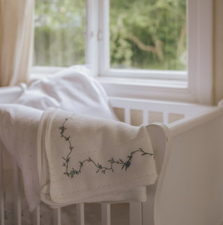 Knit Blanket with floral embroidery on white crib