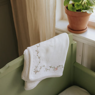 Knit Blanket with floral embroidery on a green bed by window