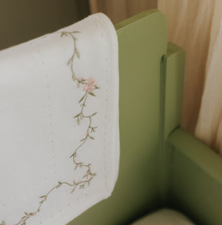 Knit Blanket with floral embroidery on a green bed