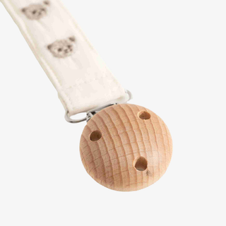 A close-up of a baby pacifier clip featuring  a white fabric strap printed with teddy bear faces.