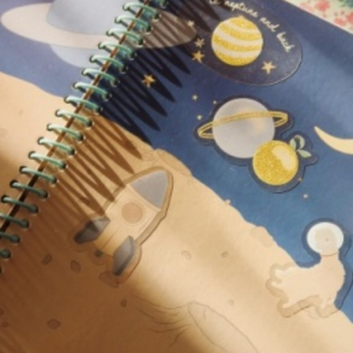 Notebook with space-themed design featuring planets and stars on a blue background.