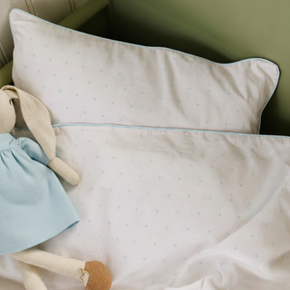 Baby pillow with soft texture and a plush toy on a green background