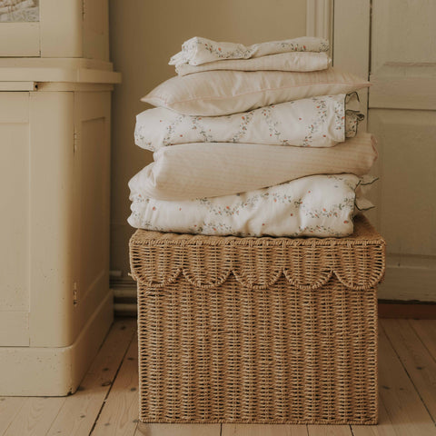 Petal Scallops Toddler Duvet in Pink piled in a stack on top of wicker basket