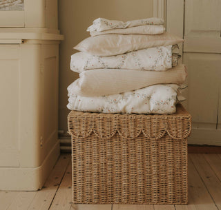 Petal Scallops Toddler Duvet in Pink piled in a stack on top of wicker basket