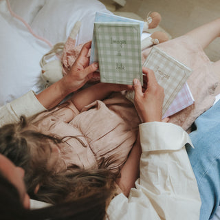 Person reading a book titled 'Images de bebe' to a child on a bed.