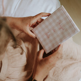Person holding a checkered photo album with 'Images de bebe' text