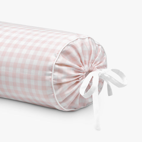 Pink checkered cylindrical pillow with a white ribbon on a light gray background