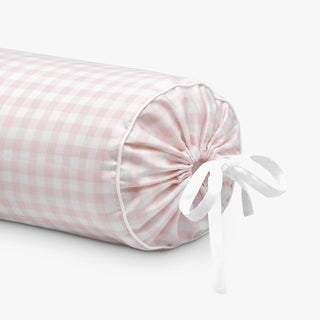 Pink checkered cylindrical pillow with a white ribbon on a light gray background