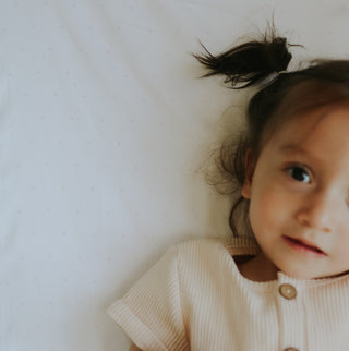 Child wearing a beige sweater with a white background