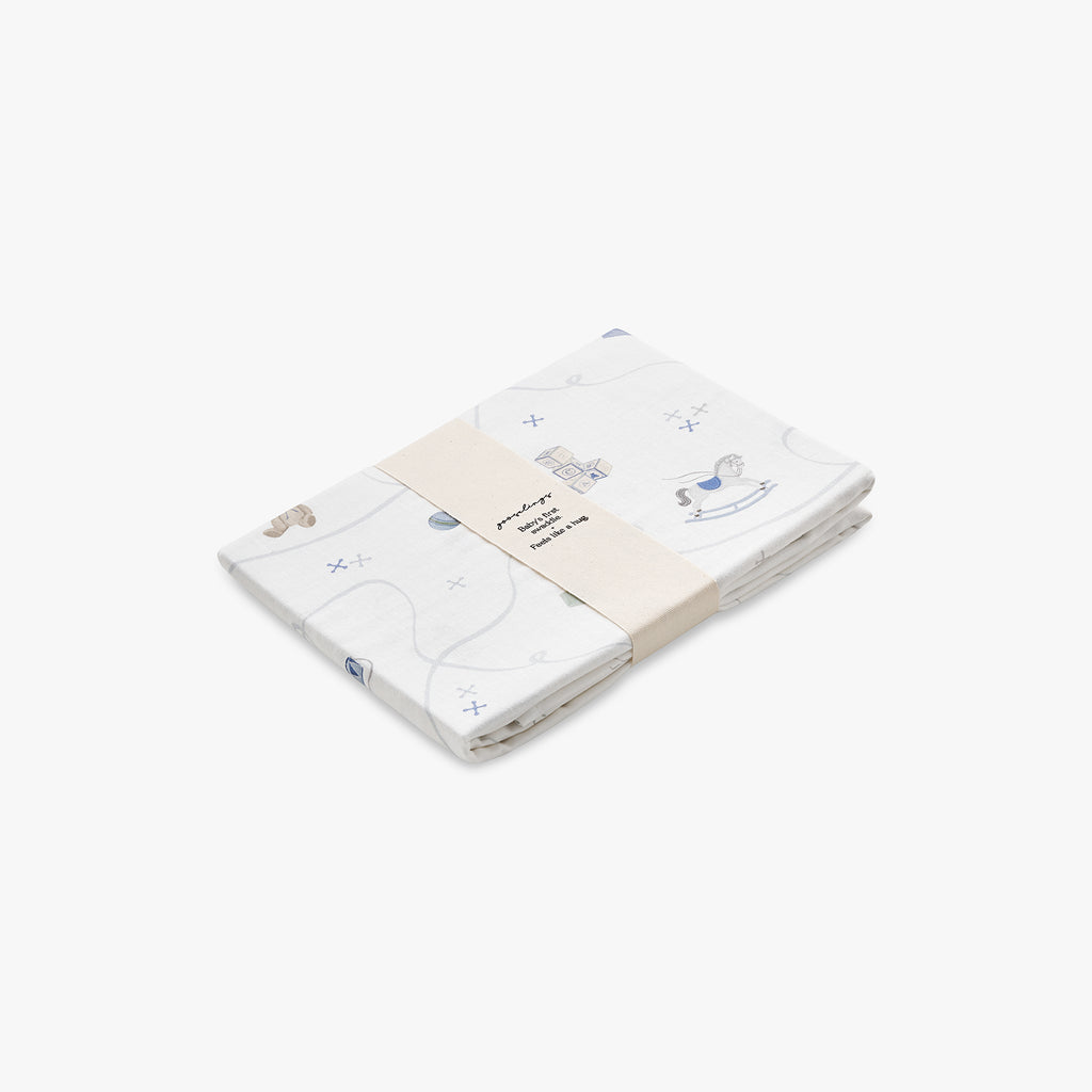 Folded baby swaddle with rocking horse and toy designs on a white background