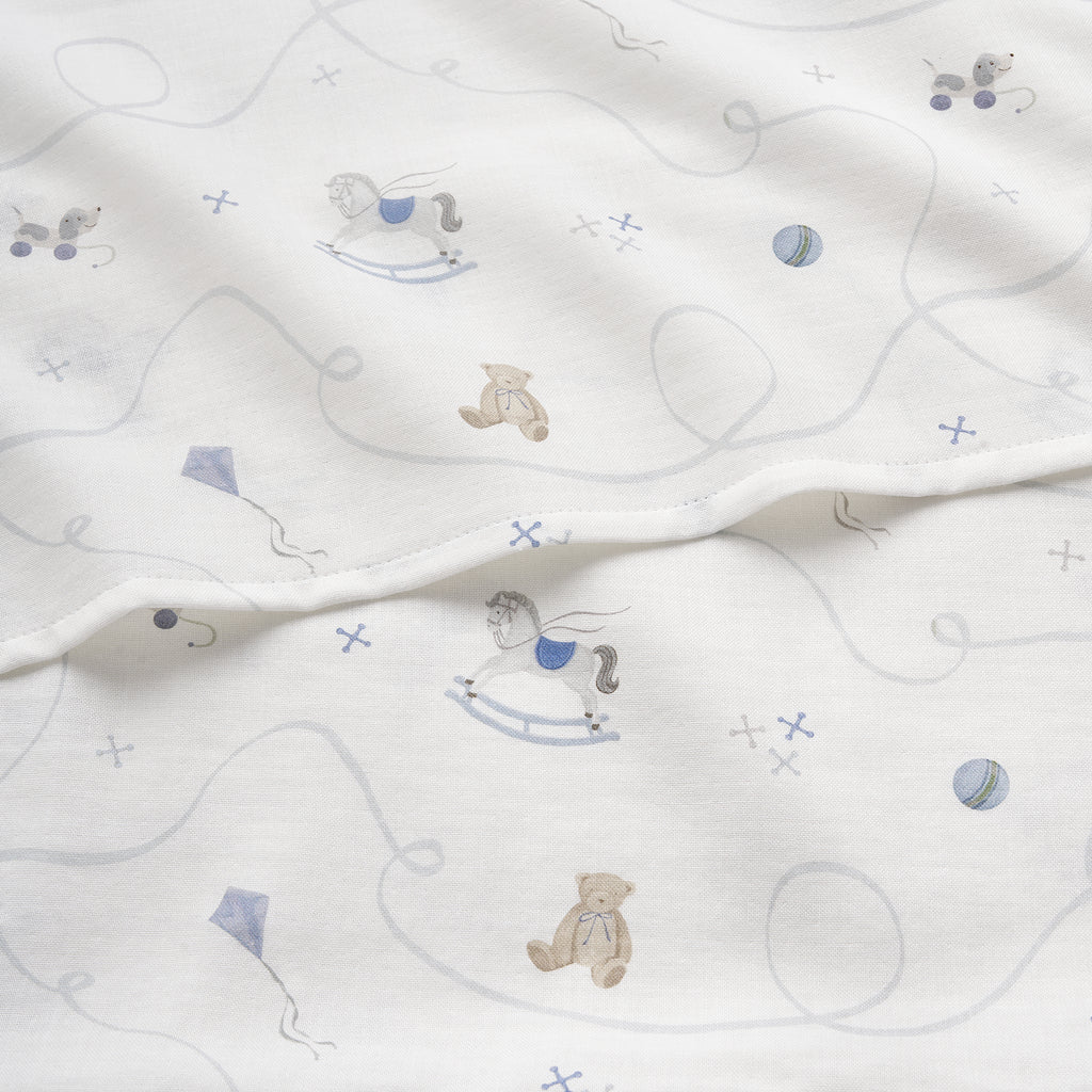 White fabric with patterns of teddy bears and rocking horses on a white background