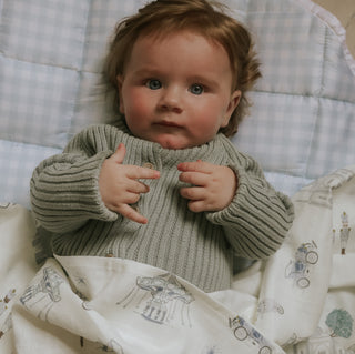 Adventures in Wonderland Swaddle Blanket in Aqua wrapped around baby