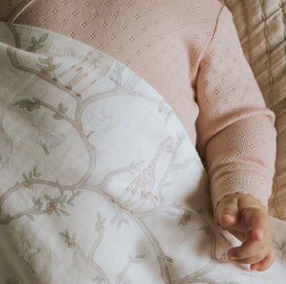 Animal Parade Swaddle in Ivory wrapped around baby