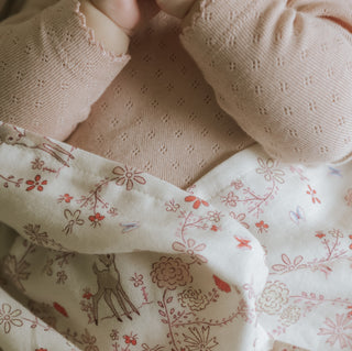 Into The Woodlands Swaddle in Ivory wrapped around baby