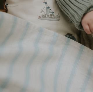 Seaside Stripes Swaddle Blanket in Blue wrapped around baby in bassinet showing up close detail