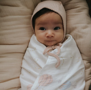 Touch The Sky Swaddle in Pink wrapped around a baby