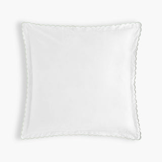 White decorative pillow with scalloped edge on a light gray background