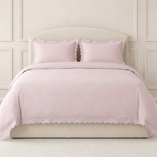 Pink bedding set on a bed with a white headboard.