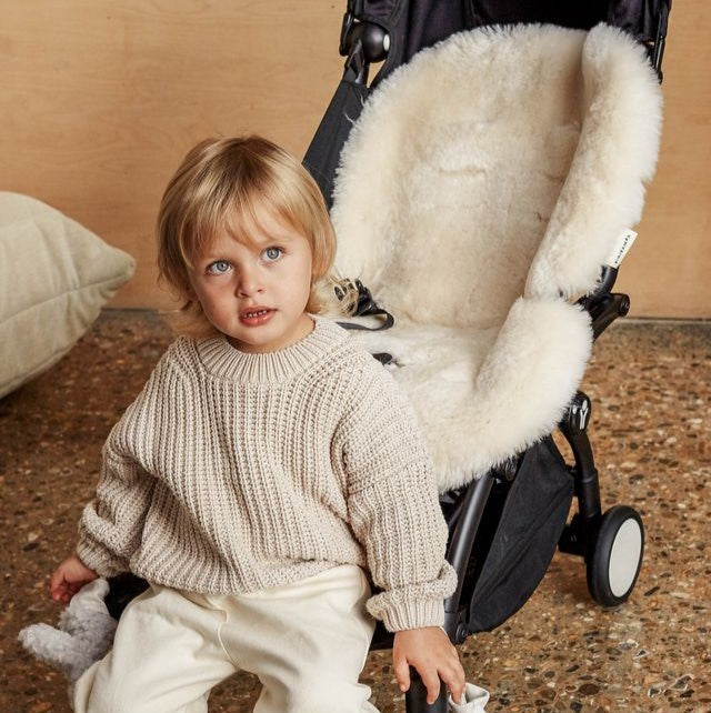 Child sitting next to a stroller with a snuggler