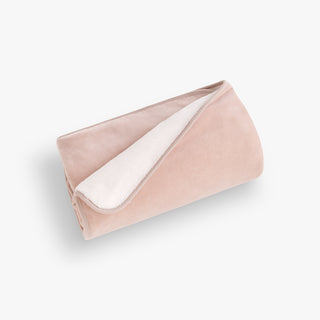 Folded blush pink blanket with white interior on a light gray background