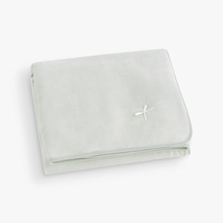 Folded light green blanket with a brand logo on a white background