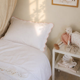 Bedroom with a bed featuring white bedding and a plush toy on a nightstand.