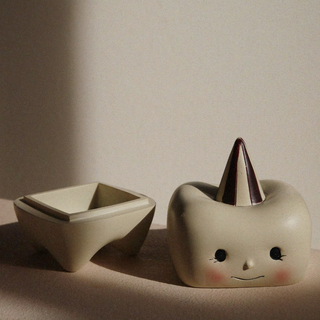 Two ceramic items, one square and one with a conical top, on a neutral background.