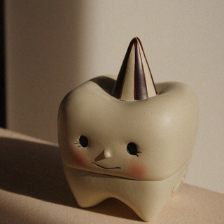 Ceramic tooth-shaped object with a horn on a neutral background
