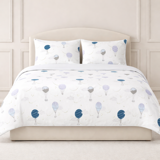 White bedding set with blue and gray balloon pattern on a bed with white pillows.