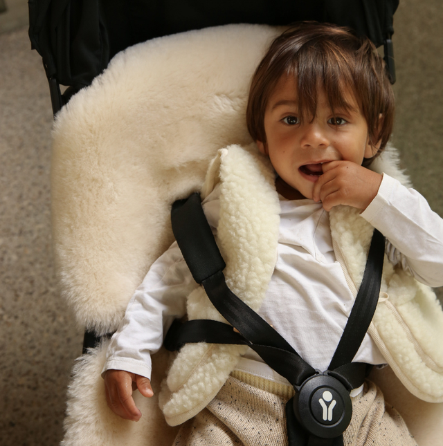 Child in a car seat with a white snuggler and black straps